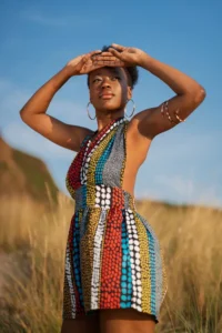 A beautiful girl standing under the sun and blocking the rays from reaching her eyes. She is wearing a Kitenge and Ankara fabrics made African fashion dress.