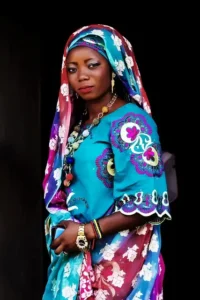 A Yoruba decent lady wearing an attire made from the African Adire. She wears a head tie and holding her shirt from drooling on the ground. © Freepik